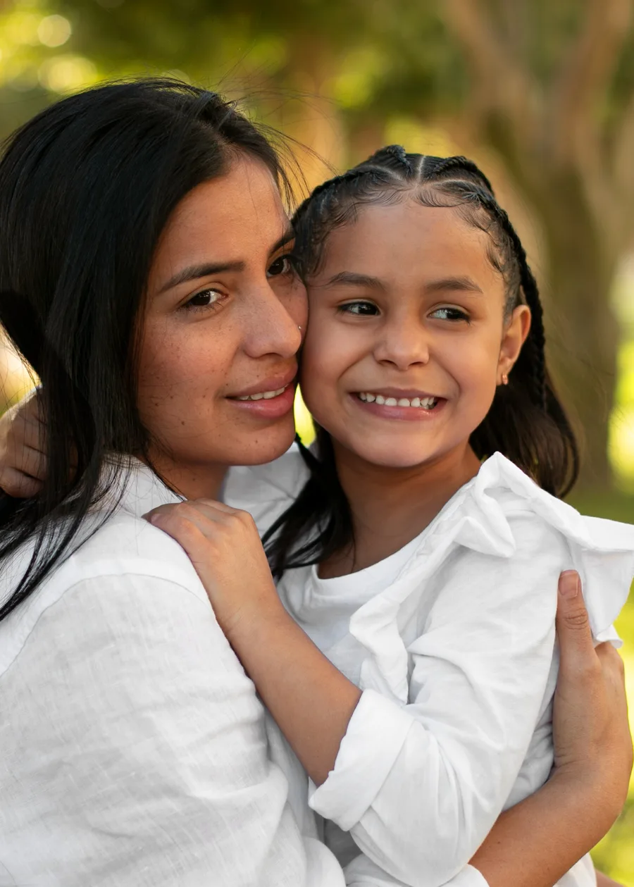A mother and daughter smiling together outdoors